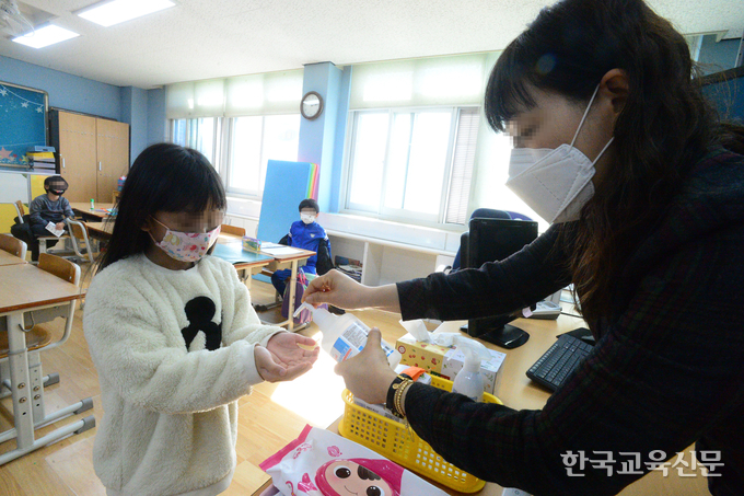 11일 오전 인천숭의초(교장 박승란) 긴급돌봄교실에서 돌봄 전담사가 등교한 학생에게 손소독을 하고 있다.