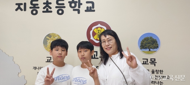 학교 중앙 현관에서 엄마와 두 쌍둥이
