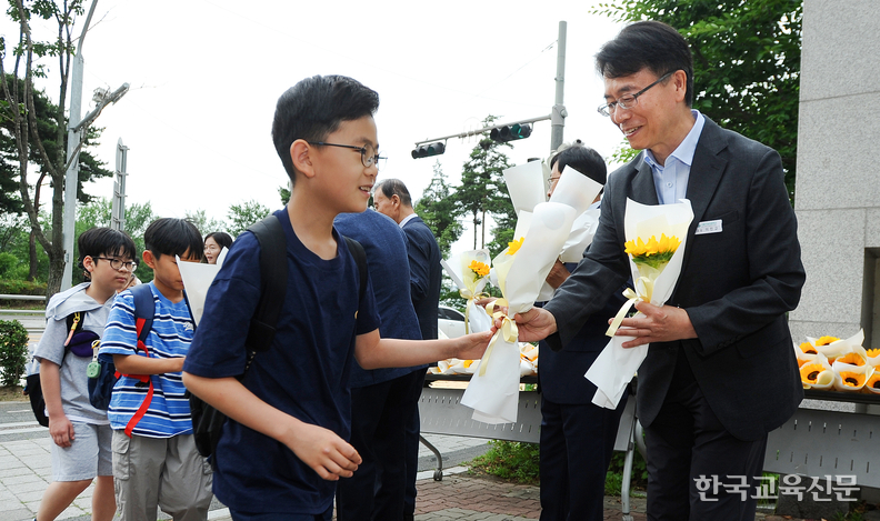 이민규(오른쪽) 교장이 등교하는 학생들에게 해바라기 꽃을 선물하고 있다.