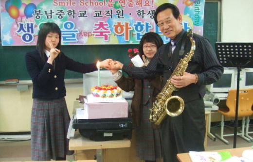 봉남중 김홍식 교장이 생일을 맞은 학생들을 위해 색소폰 연주를 들려준 후 격려하고 있다. 이 학교는 매달 교직원과 학생들을 위한 생일잔치를 연다.