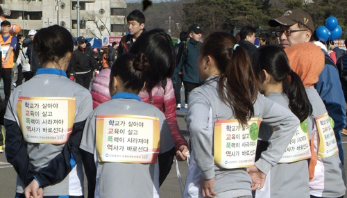 인천교총 교사와 학생들이 인천국제마라톤대회에서 학교폭력 예방 캠페인을 펼치고 있다.