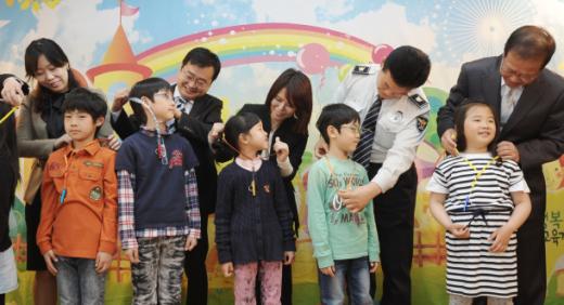 수원 대평초 ‘학교폭력 예방 우리아이 지키기 대평마을 공동체 발대식’에서 정자3동 유관기관 관계자들이 학생들에게 호신용호루라기를 전달하고 있다.