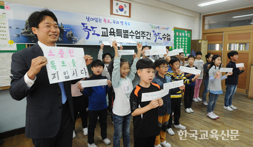 서울신봉초 김상근(왼쪽) 교사와 학생들이 독도를 지키겠다는 다짐의 문구를 쓴 종이를 들어보이고 있다.