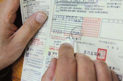 경기도의 한 초등교장이 소방관련법을 위반했다며 교장 앞으로 부과된 과태료 고지서를 보고 있다.