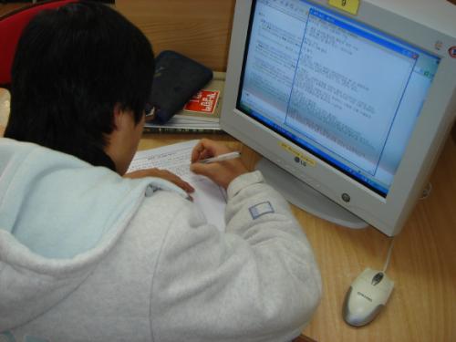 한 학생이 자기 주도적 학습 중, 인터넷 정보검색을 통해 보고서를 작성하고 있는 모습