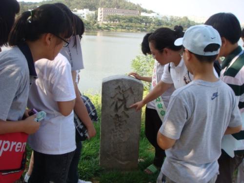 서호 제방에 있는 축만제 표지석. 우리 학교 한문교사가 학생들에게 축만제의 뜻을 설명하고 있다. 호수 건너편에는 농촌진흥청이 보인다.