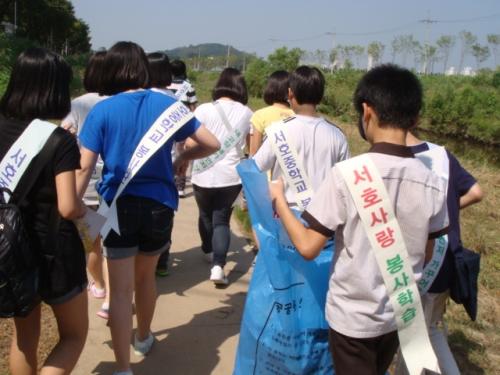 서호중학교 학생들이 학교를 출발, 서호천에서 쓰레기를 주우며 항미정으로 가고 있다. 멀리 여기산이 보인다.