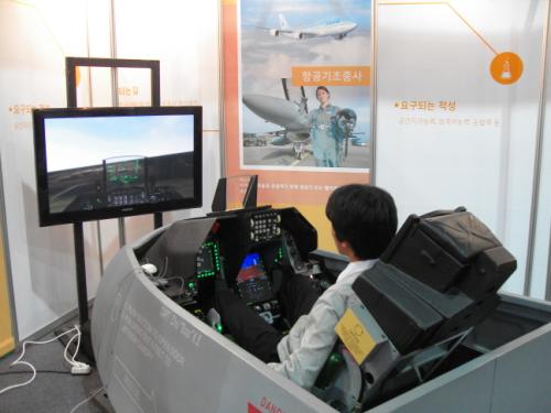 진로직업 박람회에 참가한 학생이 F16조종석에 앉아 시뮬레이션으로 직접 운전을 시연하고 있다.