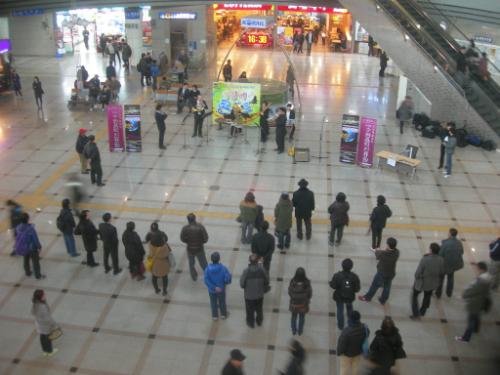여행객들이 발길을 멈추고 대합실에서 음악 감상을 하고 있다.