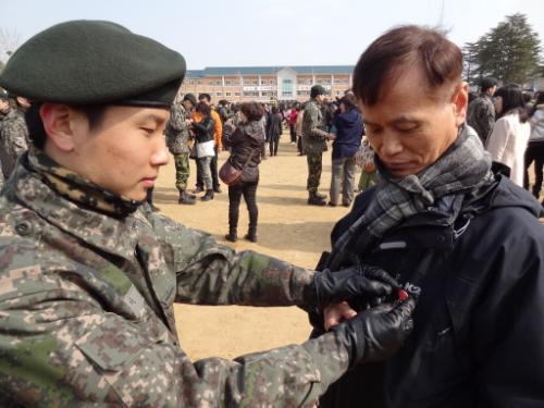 아들은 답례로 카네이션 뱃지를 아빠에게 달아준다.