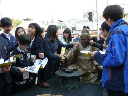 율전중 학생들이 팔달문 시장 팸투어를 하면서 정조대왕 동상에서 공부하고 있다.