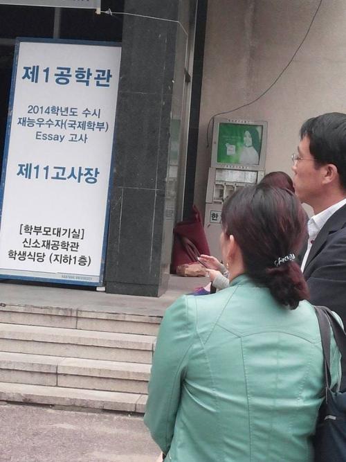 학생의 면접장에 나오신 부모님들이 면접장 밖에서 자녀들이 최선을 다하기를 바라고 있다.