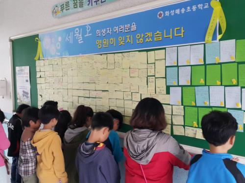 학생들이 4.16 세월호 희생자를 위한 추모게시판 앞에서 묵념하고 있다.